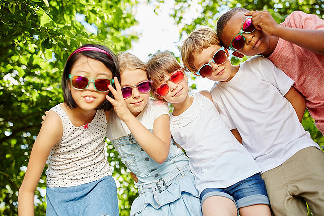 Fünf Kinder mit Sonnenbrillen schauen in die Kamera