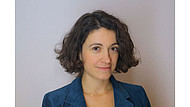 Portraitbild von Eleonora Russo. Sie hat kinnlange, gewellte, braune Haare und trägt einen blauen Blazer.